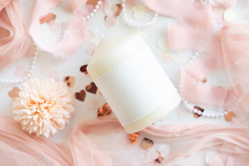Candle with blank label near pink decorations, hearts and tulle on white table top view, mockup