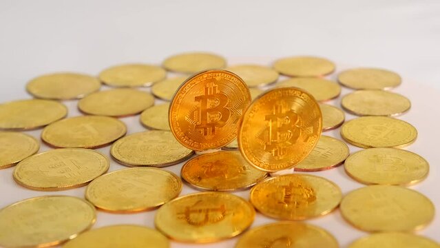 Many gold bitcoin coins moving on a white background, B-roll for cryptocurrency news