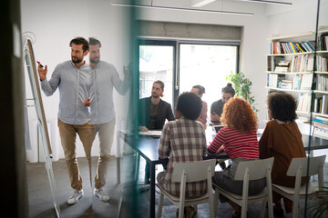Obraz premium Diverse group of happy employees analyzing reports with digital device, working together in office