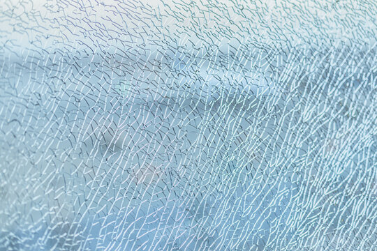 Big shattered glass window wall with many cracks and splinters that hold it together. Abstract background with a conceptual idea for designers.