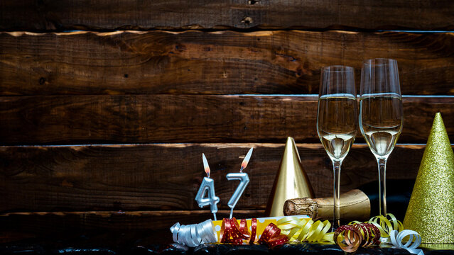 Solemn background for the anniversary with the number  47. Happy birthday background on brown wooden background with champagne bottle and champagne glasses. Beautiful holiday decorations copy space.