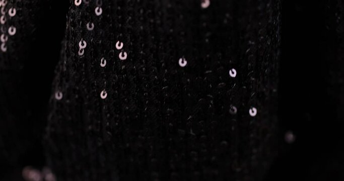 a large number of sequins on a black material, a part of the black material decorated with plastic discs to create shine