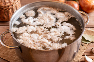 The boiling broth is filled with white bubbles floating in a pot. Some of the water sprang up with heat. Remove the foam