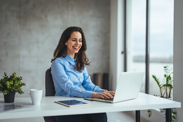 Businesswoman using laptop in office. Modern Office: Black Businesswoman Sitting at Her Desk Working on a Laptop Computer. Smiling Successful Woman working with Big Data e-Commerce.