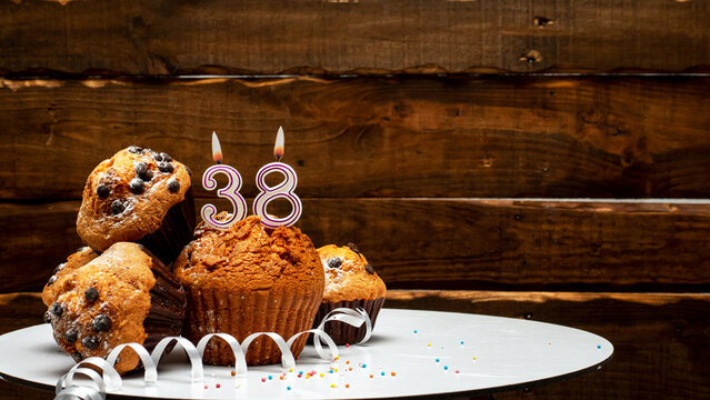 Pies with a number 38  of candles burning for the anniversary. Copy space background happy birthday on wooden background. Card or postcard festive rustic brown.