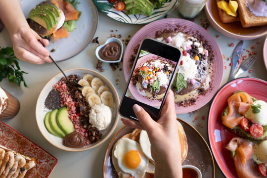 Friends taking pictures of food on the table with smartphones during brunch in restaurant