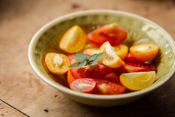 Fresh vegan tomato salad from colourful tomatoes and basil served in green bowl