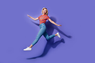 Fototapeta na wymiar Full length size photo of overjoyed funny girl run air wear denim jeans with striped t shirt carefree isolated on purple color background