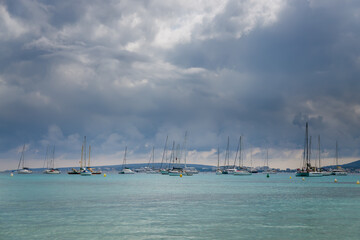Fototapeta premium A serene seascape in Mallorca with multiple sailboats, peacefully anchored on calm turquoise waters