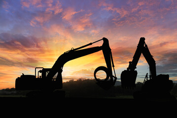 Crawler excavators silhouette are digging the soil in the construction site. on the sunset ...
