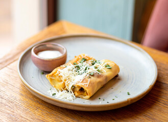 rolled pancakes with meat,bacon or cheese and parsley over. food in plate on table in cafe restaurant. sour cream in bowl and sea ​​buckthorn, blackberries red hot drink.