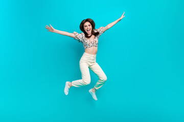 Full length photo of sweet impressed woman wear flower print top jumping high arms sides isolated teal color background