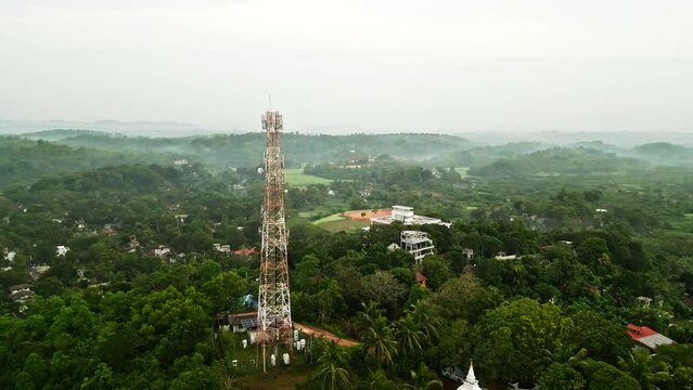 Aerial view reveals telecom tower standing amidst lush tropical foliage on secluded island. Infrastructure enables connectivity, wireless tech supported by structure. Verdant landscape antenna.