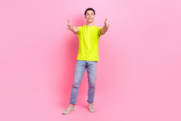 Full length photo of funky excited man dressed yellow t-shirt showing two thumbs up isolated pink...