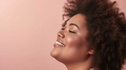 A close-up portrait of a smiling woman with a radiant complexion and voluminous curly hair set against a soft pink background exuding a sense of joy and positivity.