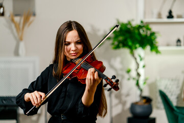 A girl violinist rehearses the melody of a classical piece of music on the violin in a music center...