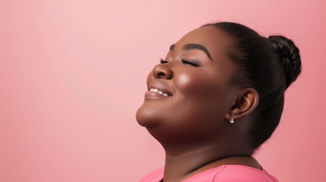 A joyful woman with closed eyes smiling and her head tilted back against a soft pink background exuding a sense of serenity and contentment.