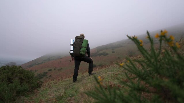 A hiker looking at low cloud before backpacking off up a hill