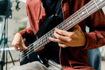 musician with electric guitar in recording studio plays musical instrument presses fingers on...