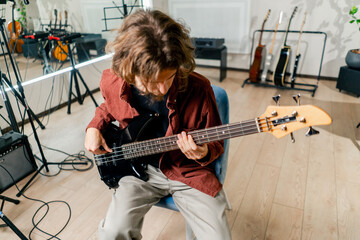 rock artist with long hair with electric guitar during rehearsal playing own track musical...
