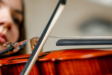 Close-up of a girl holding a violin with her fingers, fingering the strings to perform a classical musical composition