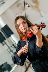 A girl violinist rehearses the melody of a classical piece of music on the violin in a music center...