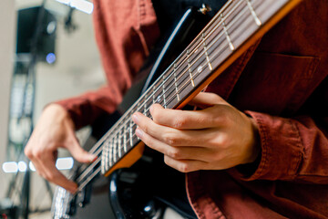 musician with electric guitar in recording studio plays musical instrument presses fingers on...