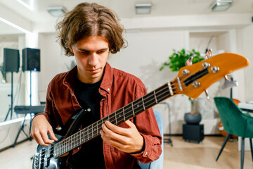 rock artist with long hair with electric guitar during rehearsal playing own track musical...