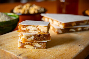 Close-up view of slices of Alajú on a wooden board, a variety of nougat traditional from the regions of Cuenca and Rincón de Ademuz in Spain - obrazy, fototapety, plakaty