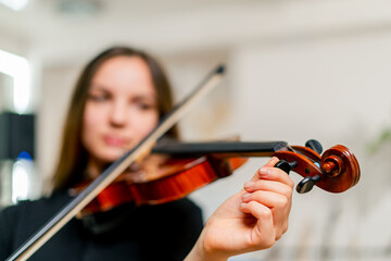 Close-up of a girl holding a violin picking strings with a bow to perform a classical music composition