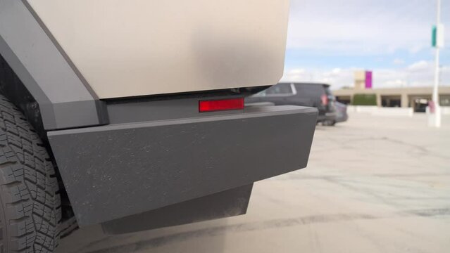 Close-up of details of a futuristic electric car with an angular design displayed outdoors.