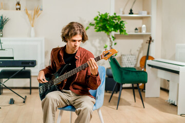 rock artist with electric guitar in recording studio playing own track musical instrument string...