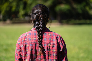 Latin woman from behind wearing a braid in a park