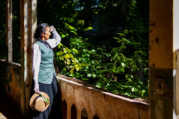 Profile portrait of a Latina woman dressed in traditional clothes, in an old train station with a lost look