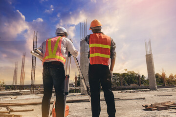 Engineer or surveyor worker working with theodolite transit equipment at outdoors construction site.