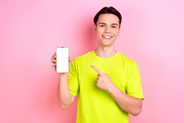 Photo portrait of nice teenager guy hold point white screen device wear trendy yellow outfit isolated on pink color background