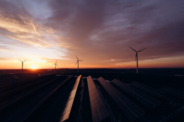 Solar panels park and wind turbines at sunset.Windmill turbines generating green energy...