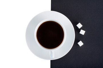 A cup of black coffee with cubes of sugar on a black and white background isolated