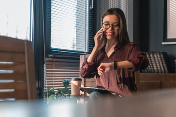 Portrait of businesswoman professional talking on cellphone and looking on watch. Deadline,...