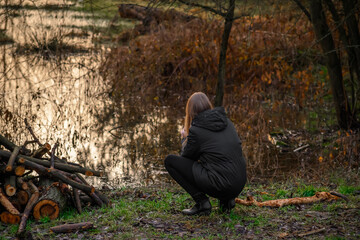 Depresja, przygnębiona kobieta patrzy na wodę, w pochmurny zimny dzień 
