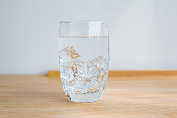 One clear glass with ice and water, Wooden floor and white background.