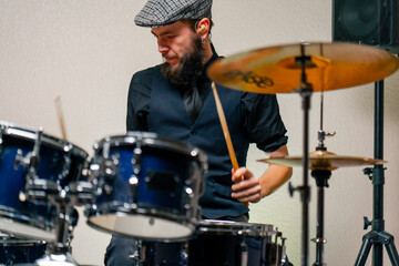 Fototapeta na wymiar bearded male musician during rehearsal plays drums musical instrument drumsticks music concert