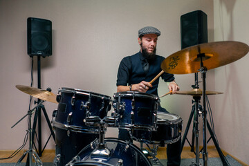 Fototapeta na wymiar bearded male musician during rehearsal plays drums musical instrument drumsticks music concert