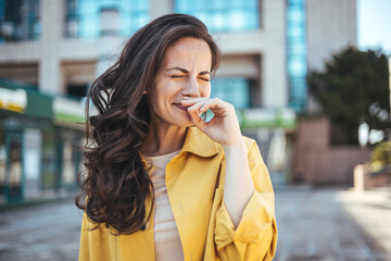 Shot of an attractive young woman feeling ill and blowing her nose with a tissue outdoors. Woman...