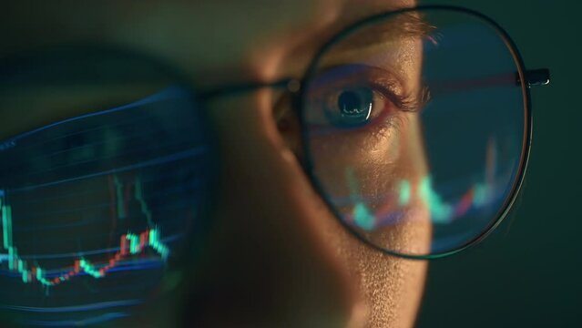 Trader wearing glasses is working on laptop computer. Screen with stock market charts and Bitcoin BTC or Ethereum ETH data analysis reflection. Broker trading online. Altcoins crypto currency trading