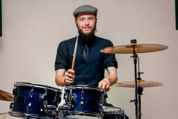 Obraz premium bearded male musician during rehearsal plays drums musical instrument drumsticks music concert