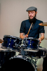 Obraz premium bearded male musician during rehearsal plays drums musical instrument drumsticks music concert