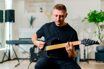 rock performer with electric guitar in recording studio playing musical instrument during rehearsal
