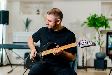 rock performer with electric guitar in recording studio playing musical instrument during rehearsal