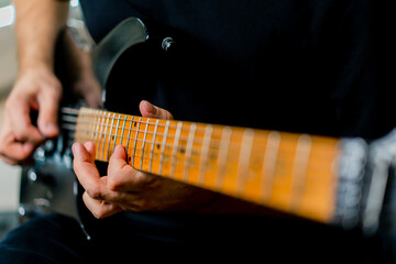 musician with electric guitar in recording studio plays musical instrument presses fingers on...